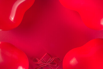 Valentine day sweet holiday background with red heart shaped balloons and gift boxes on red background top view frame copy space, mockup for Valentine’s greeting card