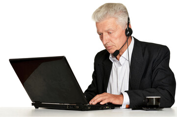 Old businessman in headphones working with laptop isolated on white background
