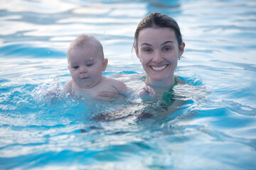 Little cute baby boy, swimming happily in a sthermal pool outdoor wintertime
