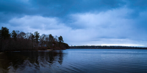Spooky cloudscape at twilight over the lake in the winter forest on Cape Cod