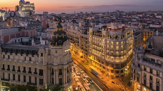 Zoom out time lapse view of sunset over historical buildings and traffic on Gran Via street in central Madrid, the capital and largest city of Spain.	