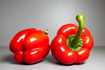 Red bell peppers with green stalks on a gray background