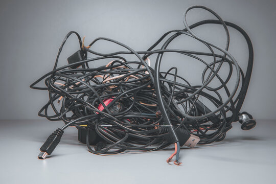 Large Chaotic Mixed Cable, Wire Node On A Gray Background. Old, Tangled Wires From Household Appliances And Gadgets