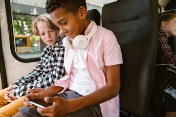 Boys using mobile phone while going on school bus