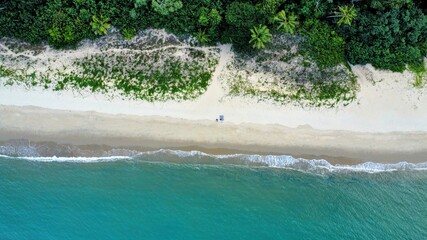 Aerial photo Ocean Meets The Rainforest with 2 People Sitting On The Beach