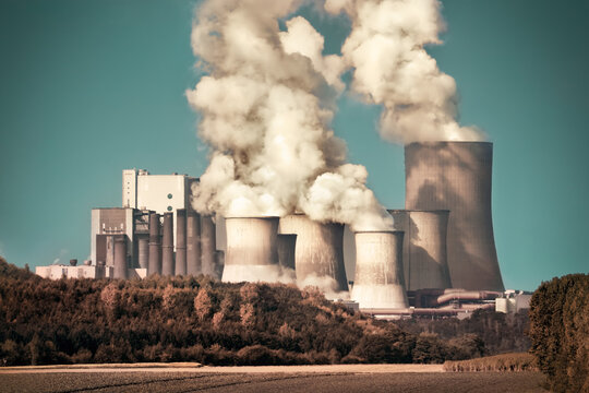Large coal power plant with steam and smoke on teal sky, dramatic look 