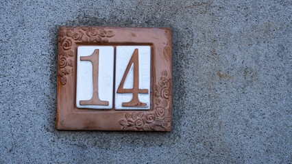 house number 14 in ceramic on gray wall. house number