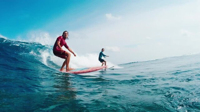 Two surfers share and ride the ocean wave in Maldives