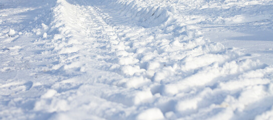 Fototapeta na wymiar Car wheel trail with deep tread in the snow, close-up, selective focus.