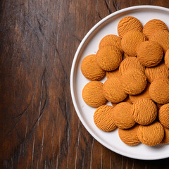 milk biscuits on a white plate, place on a wooden table top surface, closeup view of round shape snack taken from above with copy space