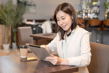 Fototapeta premium カフェでタブレットを操作する女性