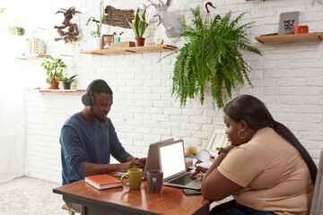 Black man and woman typing and watching on laptops