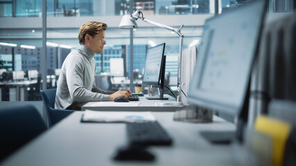 In Big Diverse Corporate Office: Portrait of Handsome Manager Using Desktop Computer, Businessman Managing Company Operations, Analysing Statistics, Commerce Data, Marketing Plans.