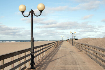 Wooden walkway on the sunny seashore. Baltic Sea, waves, sand and sky
