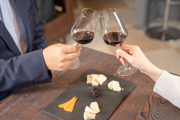 飲食店にてワインで乾杯をする男女の手元