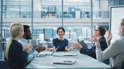 Modern Office Meeting Room: Beautiful Asian Executive Director Sits in the Head of the Conference Table and Talks to a Group of Businesspeople, Managers and Investors. People Applaud.