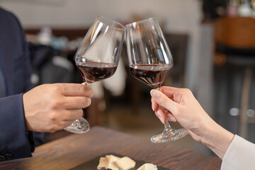 飲食店にてワインで乾杯をする男女の手元