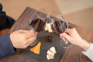 飲食店にてワインで乾杯をする男女の手元