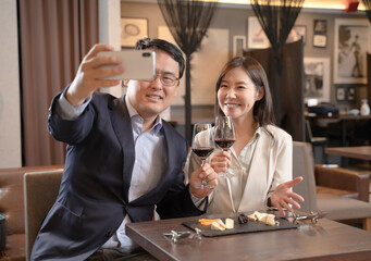 飲食店でスマホで自撮りをする男女