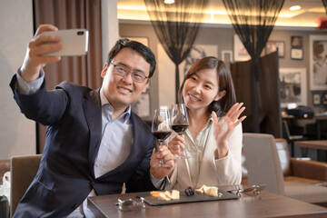 飲食店でスマホで自撮りをする男女