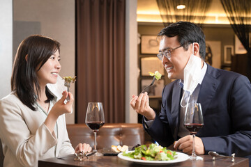飲食店でマスク会食をする男女