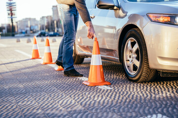 Male instructor sets the cone outdoor, driving school concept.