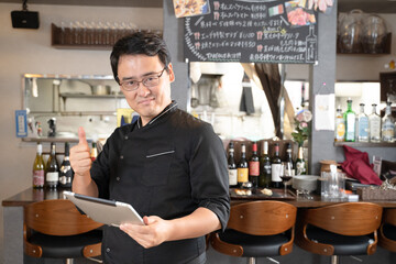 Fototapeta 飲食店でタブレットを操作する男性スタッフ obraz