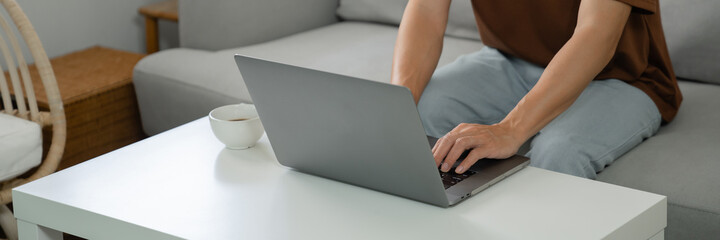 Naklejka premium Work at home young asian man working on laptop computer while sitting at home Morning lifestyle