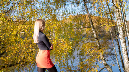 Beautiful woman against the background of the autumn forest in a red skirt