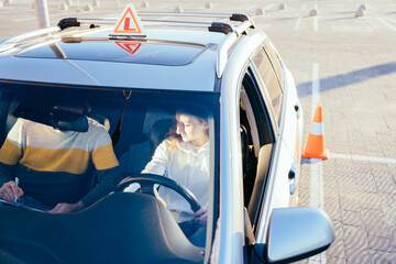 Carefully young woman in drivers seat of car taking driving lesson from instructor. Driving school...