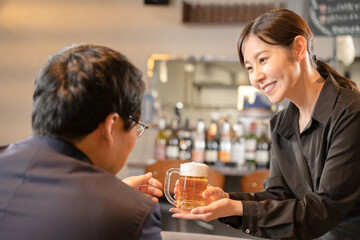 ビールを提供する女性スタッフと男性客