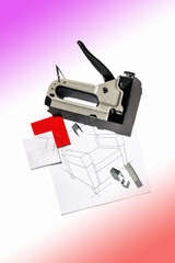 Silver furniture stapler gun with staples and the drawing of the armchair. Manual industrial tool