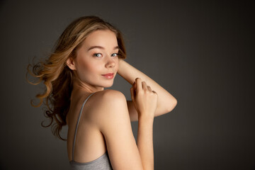 Half-length portrait of pretty caucasian girl in gray bra posing isolated over grey studio background. Natural beauty concept.
