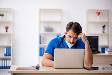 Young male doctor working in the clinic during pandemic