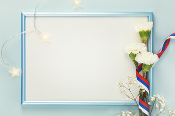 Russian holiday card with white carnations with Russian flag ribbon and blue frame on a blue background with copy space for congratulatory text suitable for 23 february, 9 may and Day of Russia