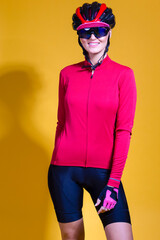 Female Cycling Ideas. Portrait of Positive Female Road Cyclist in Professional Long Sleeve Jersey Outfit Posing Against Yellow Background.
