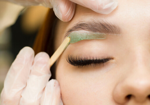 Workshop wax depilation of eyebrow hair in women, eyebrow correction. Green wax