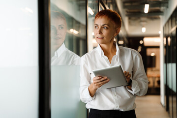 Mature serious woman working with tablet computer