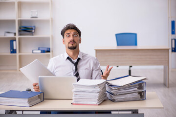 Obraz premium Young male employee and too much work in the office