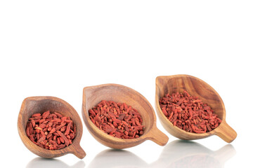 Obraz na płótnie Canvas Dried sweet goji berries in three wooden cups, macro, isolated on white.