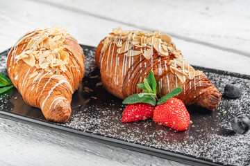 Fresh sweet croissant with berries and powdered sugar on a plate. Baked croissant for breakfast...
