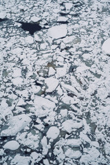 The ice on the river is split into small pieces.  floes ice on a pond in winter, texture.