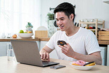 Asian business man eating unhealthy junk food while working from home.