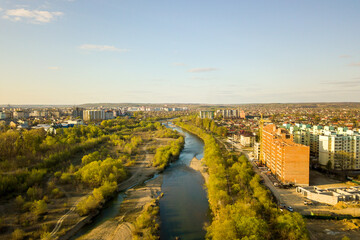 Fototapeta premium Aerial view of tall residential apartment buildings under construction and Bystrytsia river in Ivano-Frankivsk city, Ukraine