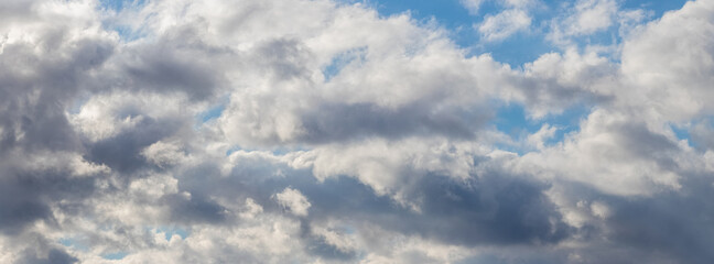 White fluffy clouds densely cover the blue sky, panorama