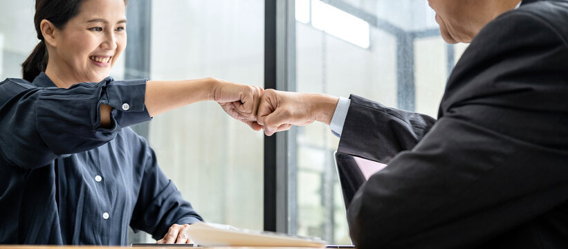 Business team is checking business document together and making a fist-bump after mission complete