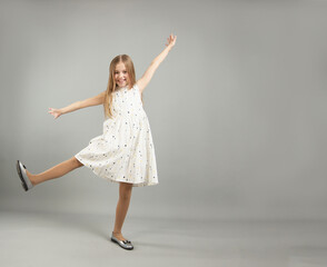 Naklejka premium the concept of happiness, freedom, power, movement and people - a smiling young girl jumps in the air on a gray background