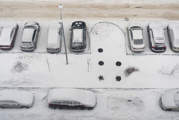 Snowy winter in the city. Top view of the parking lot. Road is covered snow, car