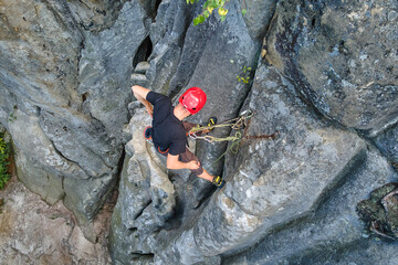 Strong male climber climbing steep wall of rocky mountain. Sportsman overcoming difficult route. Engaging in extreme sports hobby concept