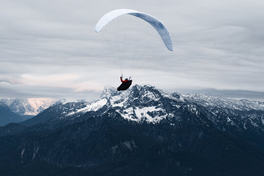 Paraglider flying over village near mountains